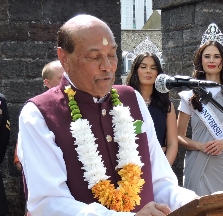 Raj stood in front of mic reading at an event in Wales